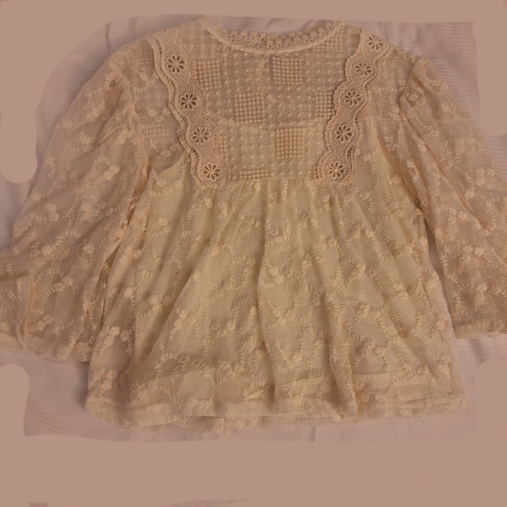 A sort of clear top with white flower design and a sleeveless top under.
